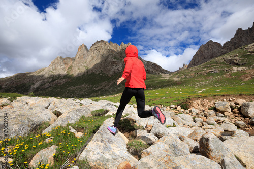 young woman trail runner running at high altitude mountains