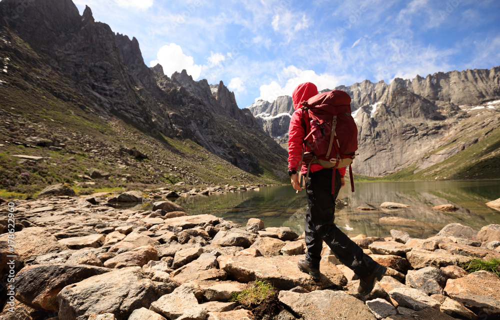 woman hiker with backpack hiking at high altitude mountains