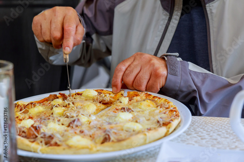 Close-up of a male chef cutting a pizza in kitchen