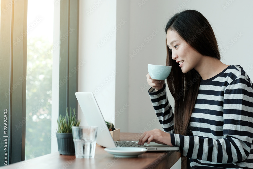 Young asian woman using laptop computer and drinking coffee at cafe background, people and technology, lifestyles Young asian woman using laptop computer and drinking coffee at cafe background, people and technology, lifestyles