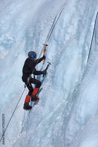 An ice climber makes his way on a frozen waterfall.