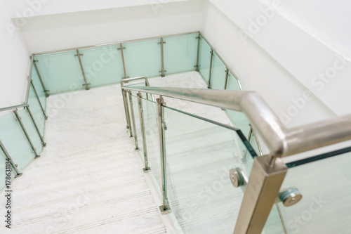 Modern white marble stairs with steel and glass railing in a new modern building.