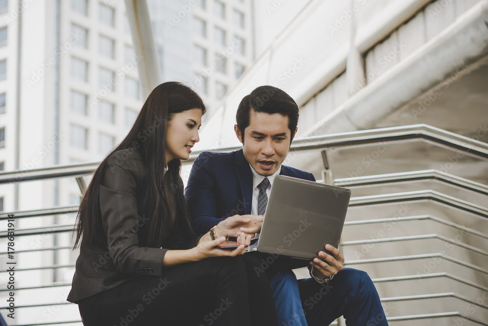 Business coworkers discussing new ideas and brainstorming on laptop sitting on staircase office Business coworkers discussing new ideas and brainstorming on laptop sitting on staircase office