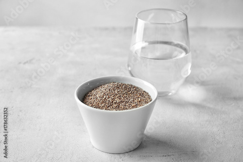 Bowl with chia seeds and glass of water on table
