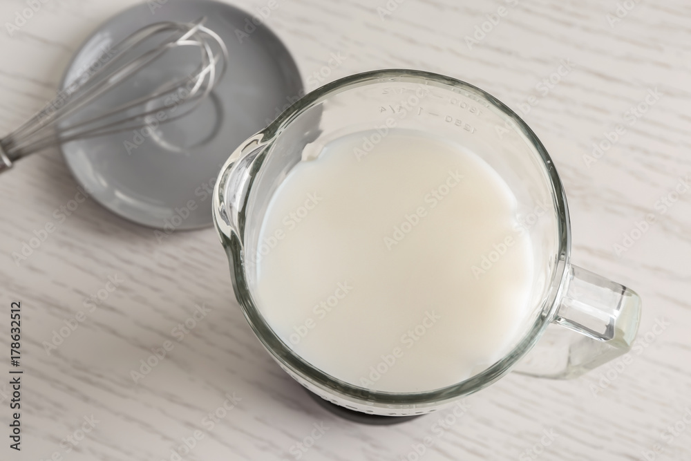Glass jug with yogurt for making pudding on wooden table Glass jug with yogurt for making pudding on wooden table