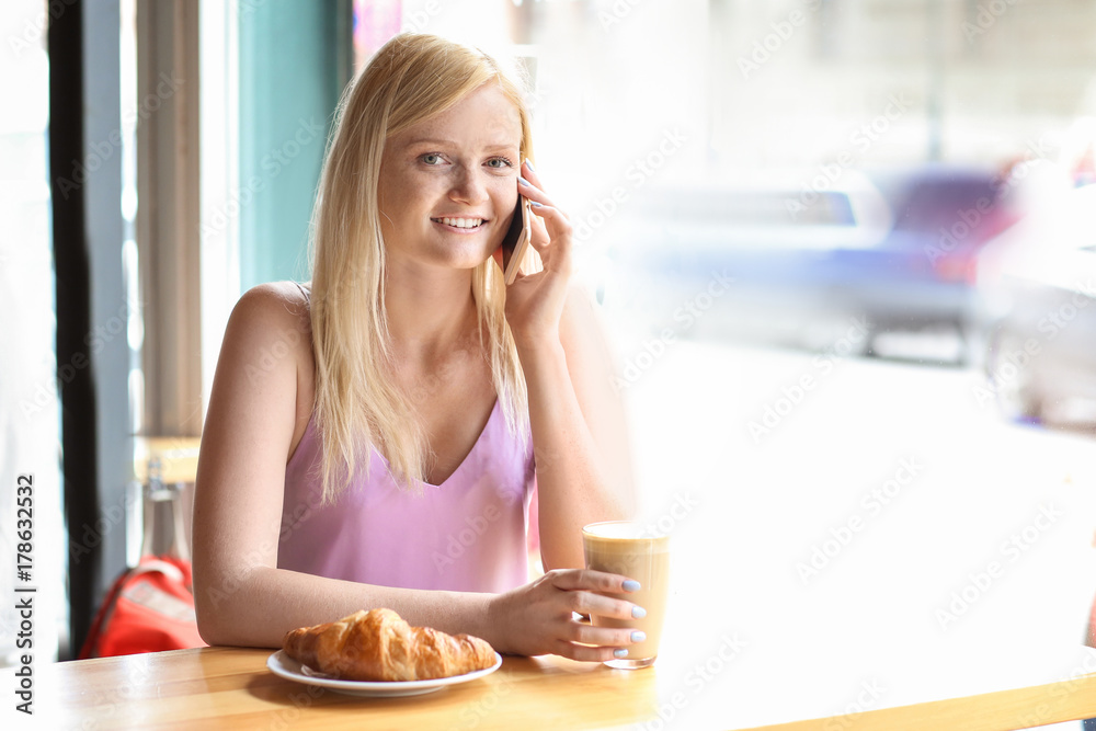 Beautiful young woman talking on mobile phone in cafe Beautiful young woman talking on mobile phone in cafe