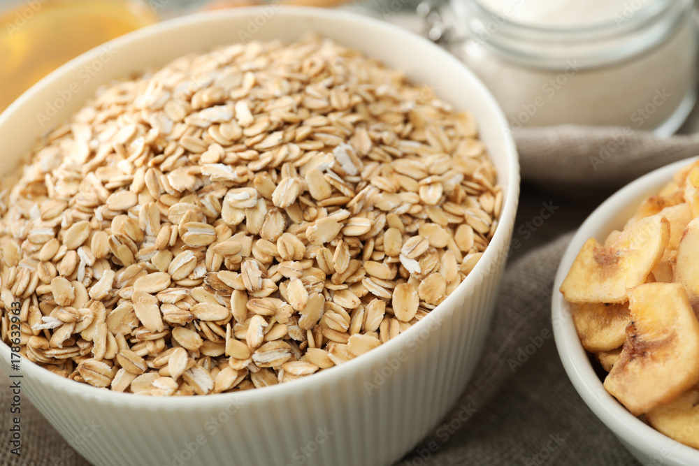 Bowl with oatmeal flakes on fabric, closeup Bowl with oatmeal flakes on fabric, closeup