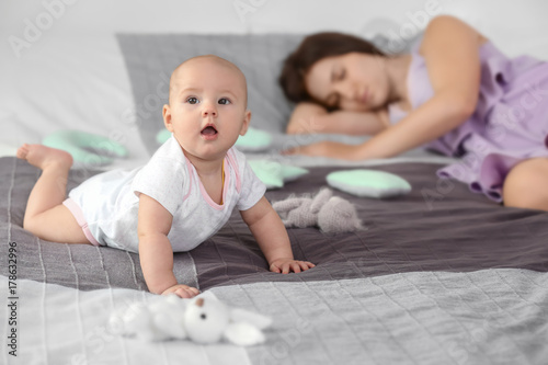 Slika na platnu Cute awaken baby near sleeping mother at home
