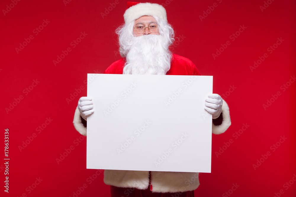 Santa Claus pointing in blank advertisement banner isolated on red background with copy space Santa Claus pointing in blank advertisement banner isolated on red background with copy space