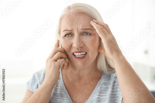 Senior woman speaking on ce...