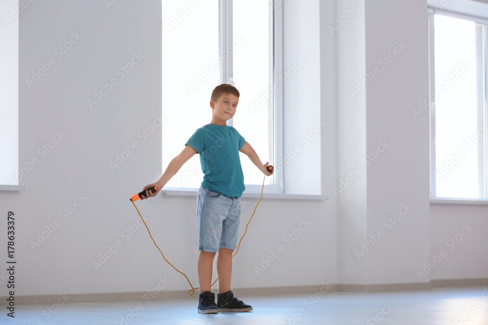 Fototapeta premium Adorable boy skipping rope indoors