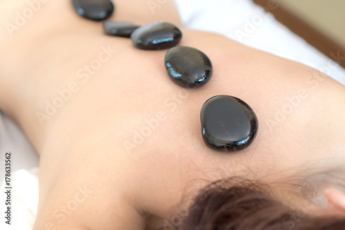 close up beautiful and healthy woman during a back stone therapy massage in spa salon