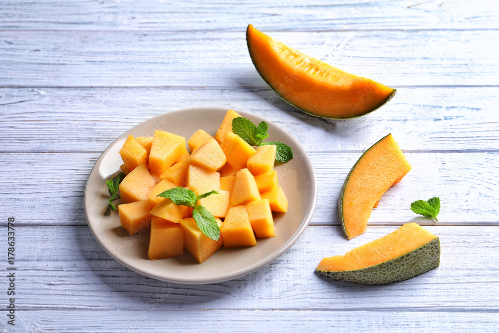 Plate with sliced melon on wooden background