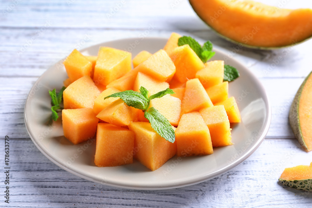 Plate with sliced melon on wooden background, closeup Plate with sliced melon on wooden background, closeup