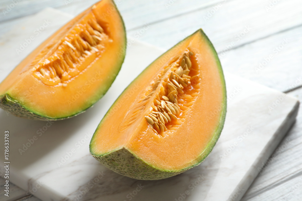 Marble board with slices of fresh ripe melon on table, closeup Marble board with slices of fresh ripe melon on table, closeup