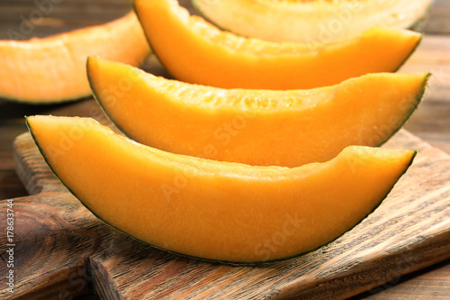 Wooden board with sliced melon on table, closeup