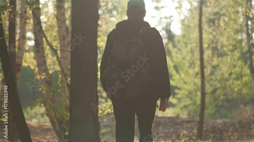 A man with a backpack walks through the autumn forest. A traveler walks in nature. Hitchhiker walks among the trees. photo