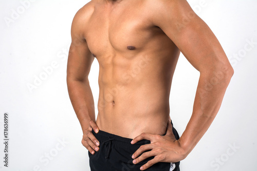 Muscular man showing six pack abs isolated on white background.