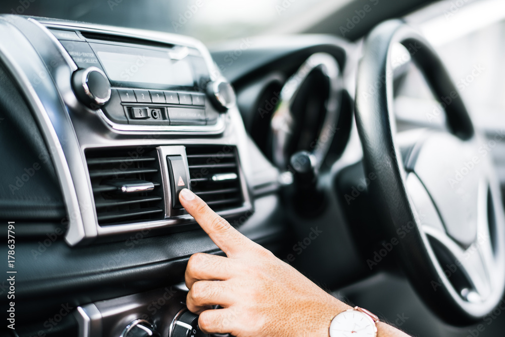 Hand of man turning on car air conditioning system,finger hitting car emergency light botton,Hand tuning fm radio button in car panel.