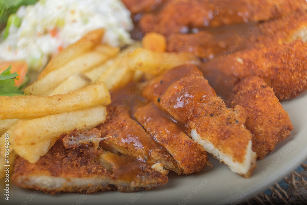 Chicken chop with vegetable and black pepper sauce in plate over wooden table Chicken chop with vegetable and black pepper sauce in plate over wooden table