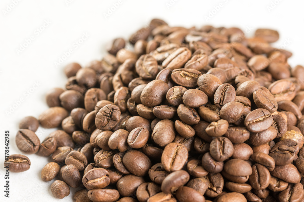 Naklejka premium Pile of coffee beans isolated above white marble background