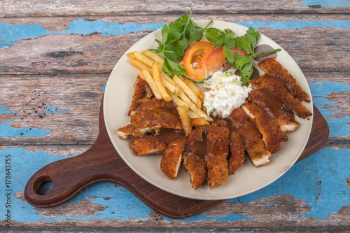 Top view of  chicken chop with vegetable and black pepper sauce in plate over wooden table
