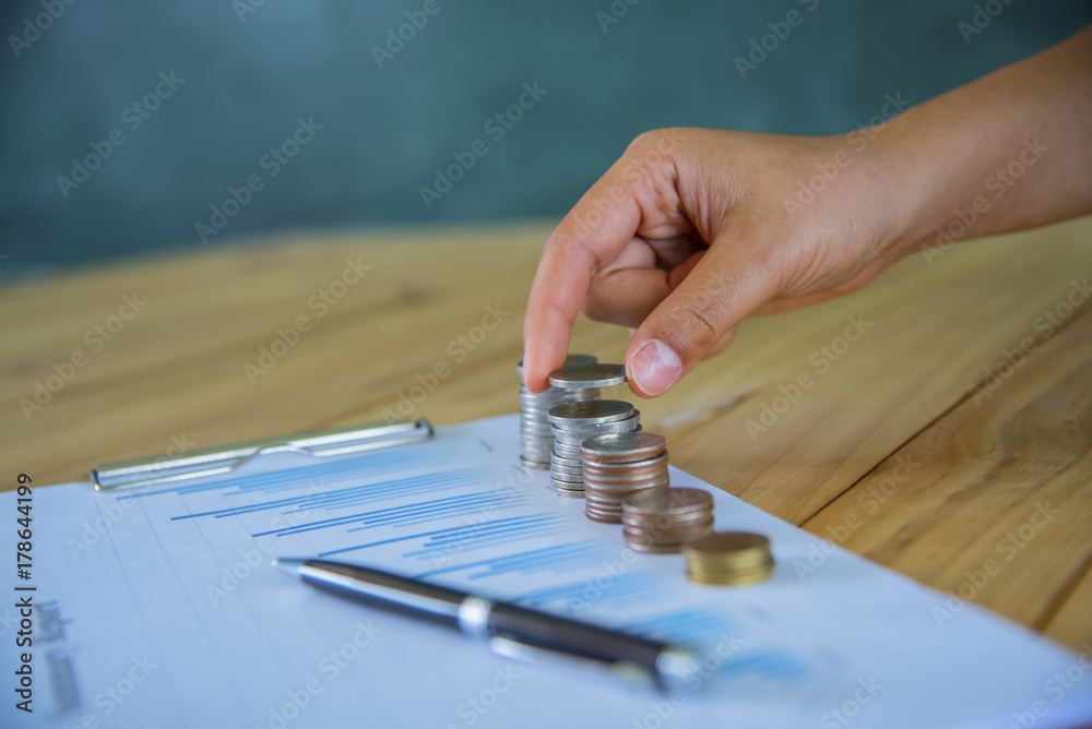 close up Hand putting money coins stack in saving money and growing business concept