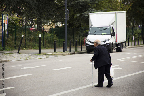 French old man walking crossing traffic road at Paris zone 5