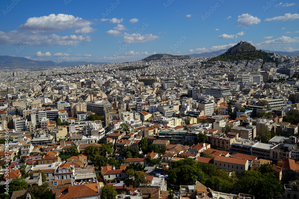 View of beautiful Athens cityscape from Acropolis seeing lowrise building architecture, Mount Lycabettus, mountain, blue sky and floating white cloud background
