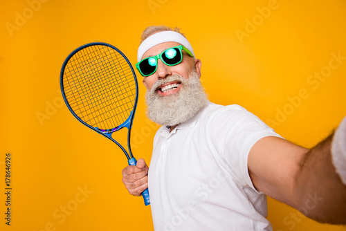 Competetive emotional cool grandpa with humor grimace exercising holding equipment, shoting photo. Body care, healthcare, weight loss, game, coach, champion, funky lifestyle