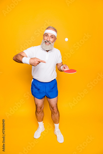 Healthcare, weight loss, bodycare lifestyle. Competetive emotional cool active goofy comic grey haired grandpa with humor grimace and beaming grin, with table tennis equipment, plays it