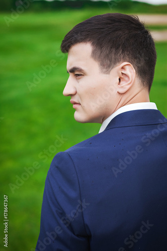 Portrait in profile of handsome groom on the meadow