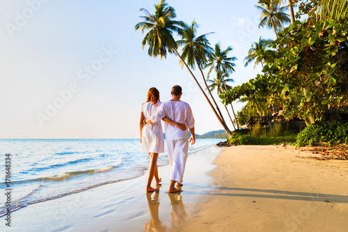 Romantic couple walking together on tropical beach, sunny summer honeymoon photo