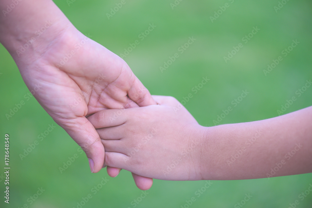 Mother holding a hand of his son with green glass background. Love , famiy and mother day concept. Mother holding a hand of his son with green glass background. Love , famiy and mother day concept.