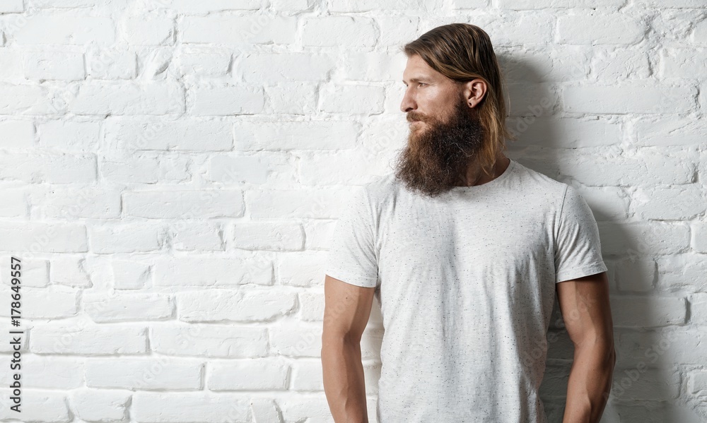 Obraz premium Trendy young bearded man against white brick wall
