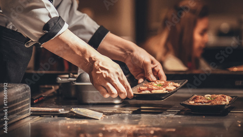 Hand of man take cooking of meat with vegetable grill, Chef cooking wagyu beef in Japanese teppanyaki restaurant photo