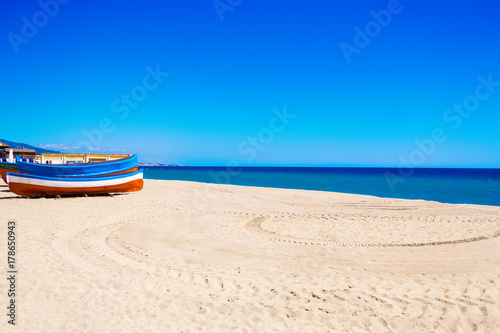 Sea Beach and Soft wave of blue ocean.  Summer day and sand  background. Colorful boat and empty beach. © nataliazakharova