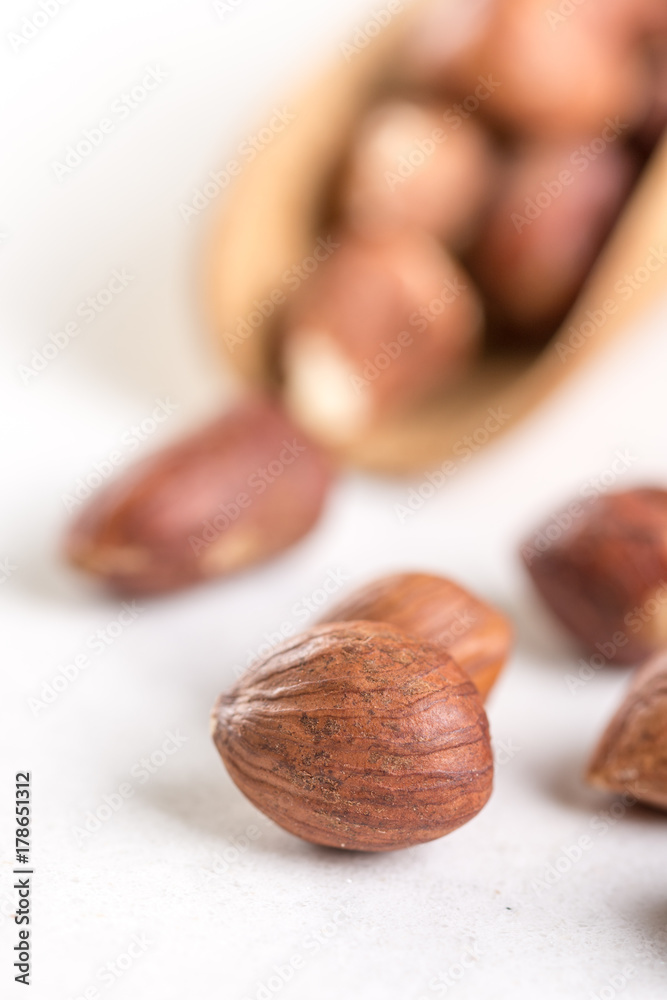 Raw hazelnuts on the white background with wooden spatula spoon Raw hazelnuts on the white background with wooden spatula spoon
