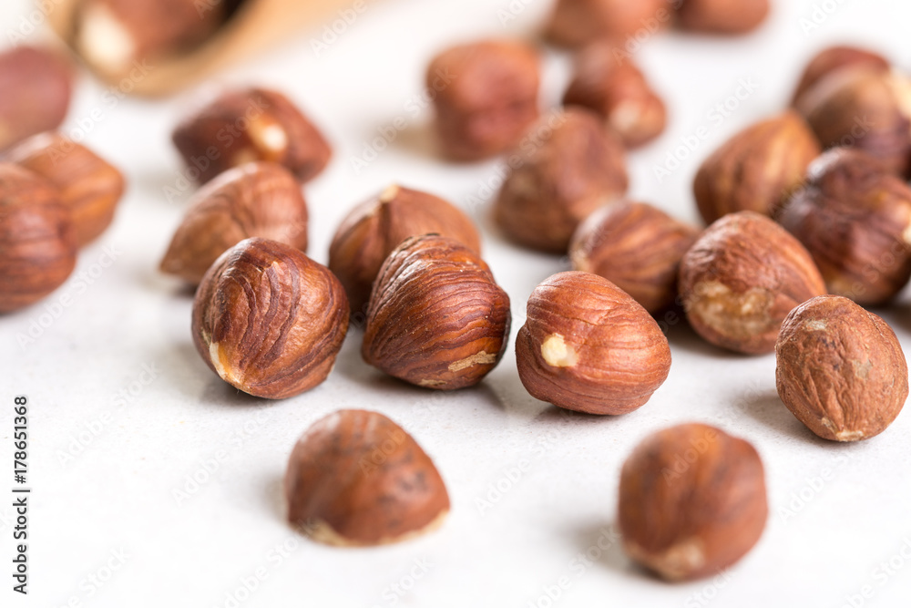 Closeup macro of raw hazelnuts on the white marble background Closeup macro of raw hazelnuts on the white marble background