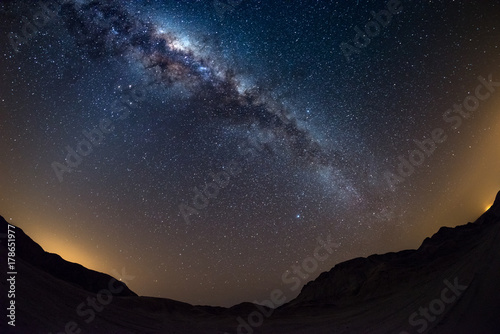 Starry sky and Milky Way arch, with details of its colorful core, outstandingly bright, captured from the Namib desert in Namibia, Africa. The Small Magellanic Cloud on the left hand side. photo