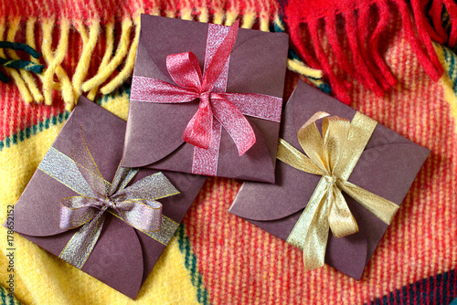 Holiday gifts for Christmas and New Year on the background of plaid in red and yellow colors.