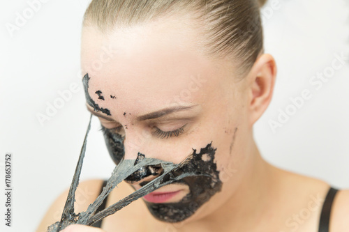 Woman with purifying black mask on her face
