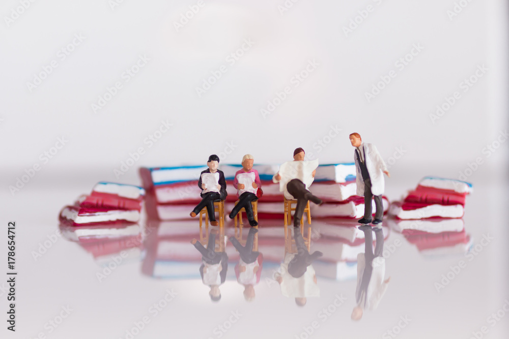 Fototapeta premium Miniature people sitting on book using as background education or business concept