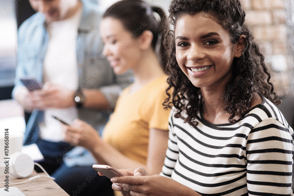 Alert smiling girl sitting and holding her phone Alert smiling girl sitting and holding her phone