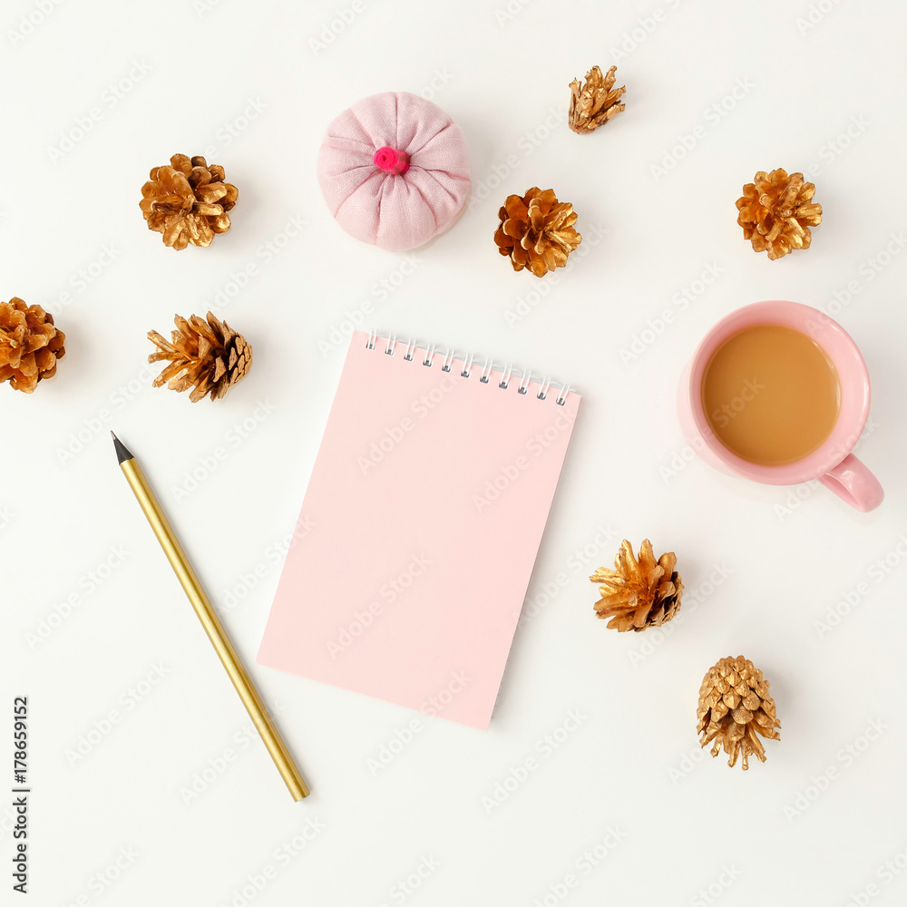 Feminine desktop with golden pine cones, pink notebook, coffee c Feminine desktop with golden pine cones, pink notebook, coffee c