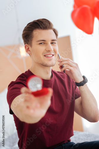 Obraz na plátně Beaming guy showing proposal ring during phone conversation