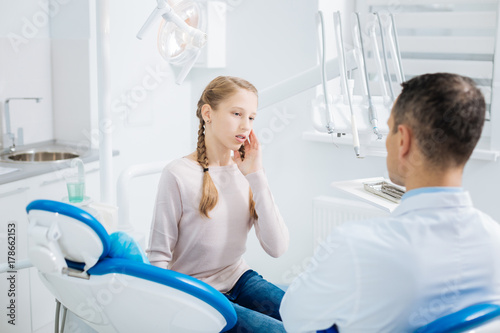 Cheerless young girl having a tooth pain