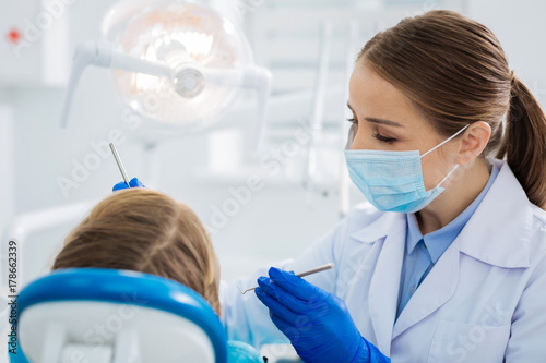 Pleasant professional dentist doing her job