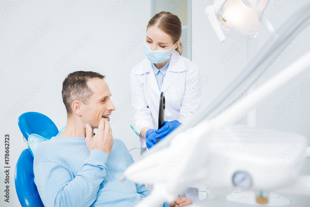 Nice positive man looking at his tooth Nice positive man looking at his tooth