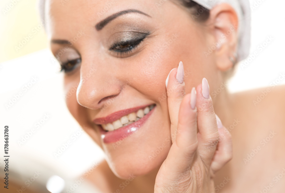 Portrait of smiling young woman applying moisturizing cream